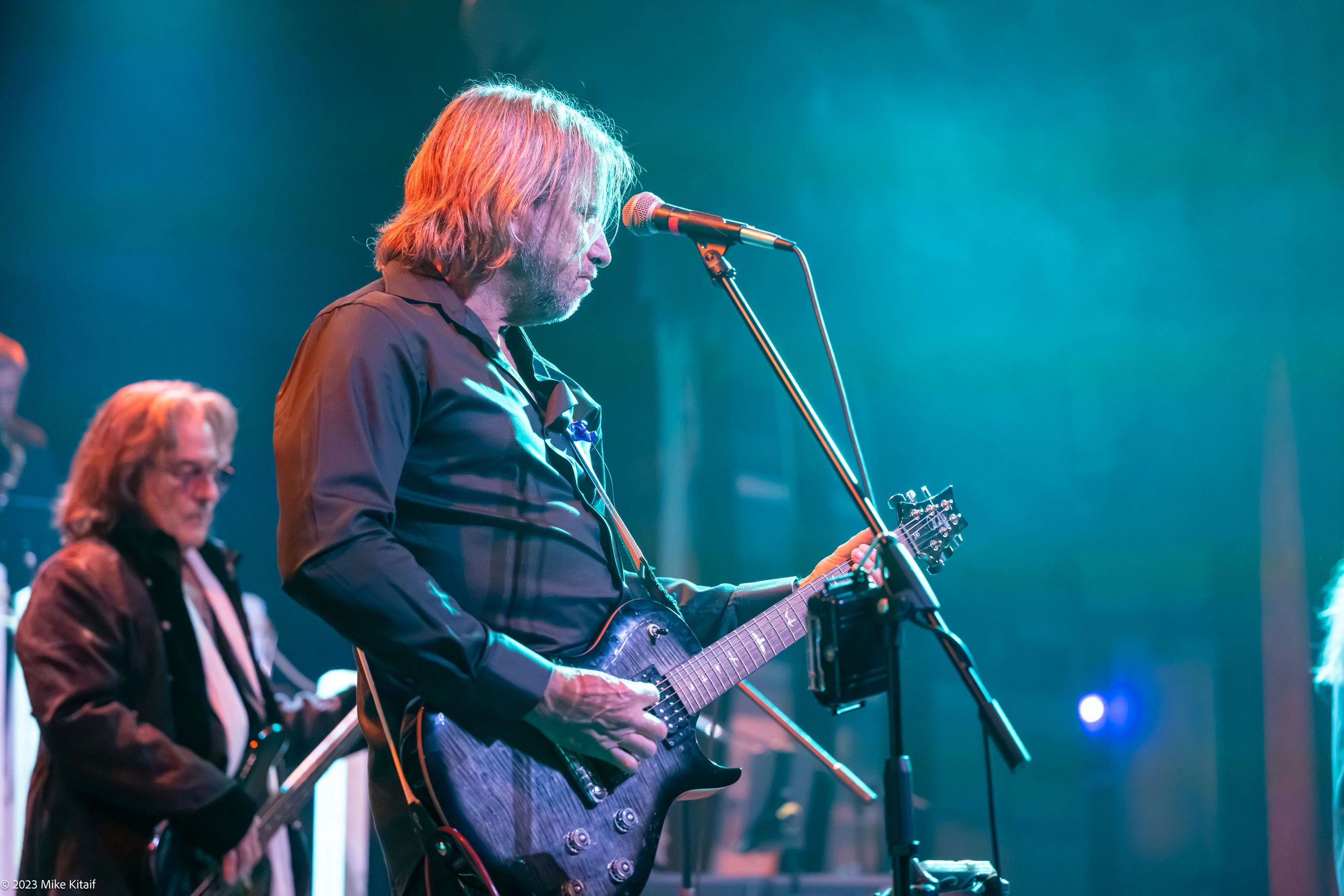 Lead vocalist performing with teal and orange stage lighting