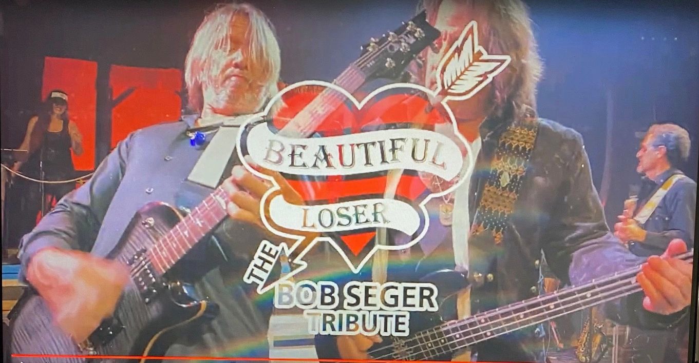 Two guitarists performing together under red and blue stage lighting